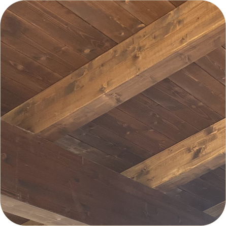 Soffitto con travi in legno scuro a vista, che mostra la solidità e l'aspetto naturale del legno.