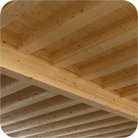Soffitto in legno con travi ravvicinate, che mostra una struttura robusta e ben rifinita in legno naturale chiaro.